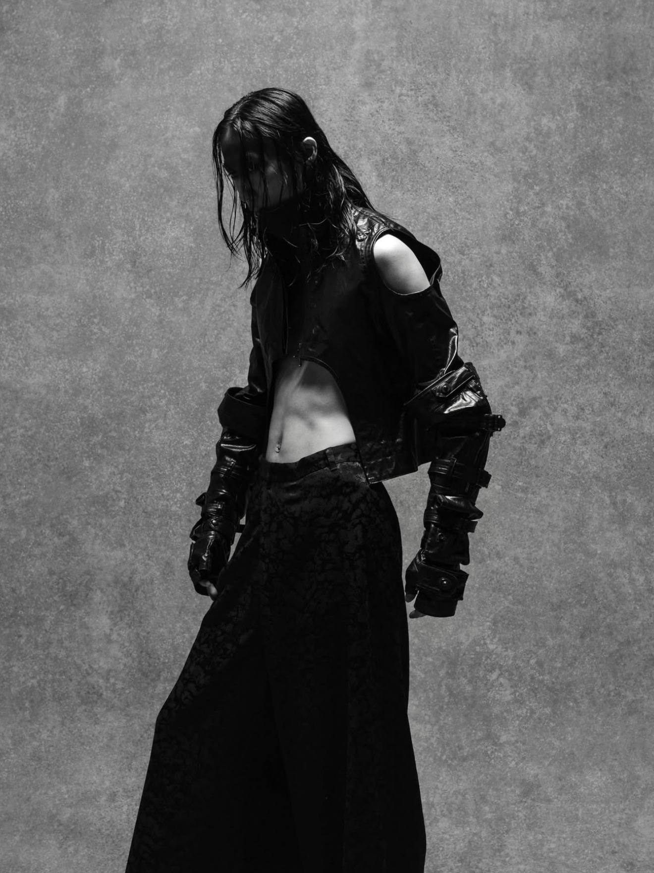 Avant-garde fashion model in a cropped black jacket with cut-out shoulders and wide-leg pants